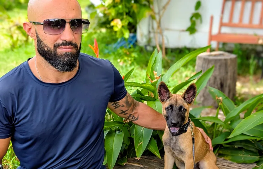 Charles V. outdoors in a garden with his young Belgian Malinois, Da Nang 2024
